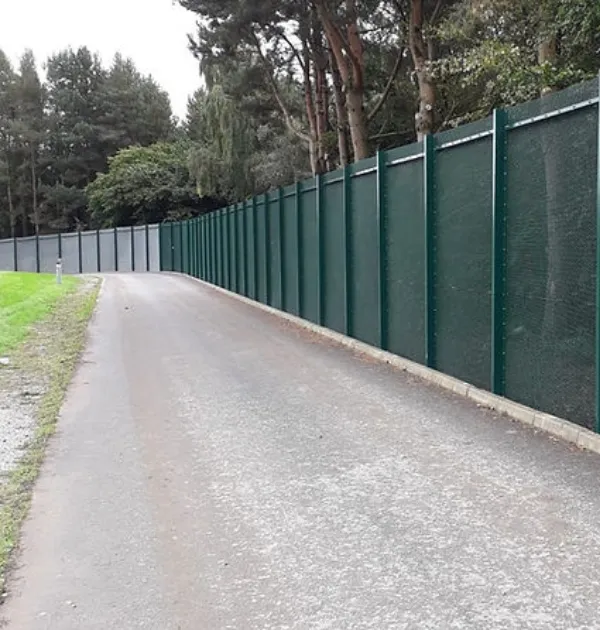 Green high-security mesh and privacy panel perimeter fence along a service road at a Severn Trent Water facility in the UK