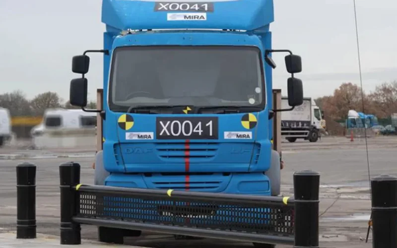 PAS 68 bollard crash test with a 7.5 tonne MIRA test truck approaching a surface-mount security bollard array