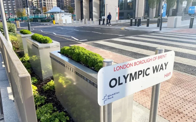 PAS 68 impact-tested stainless steel security planter shrouds with planted greenery on an urban pedestrian boulevard