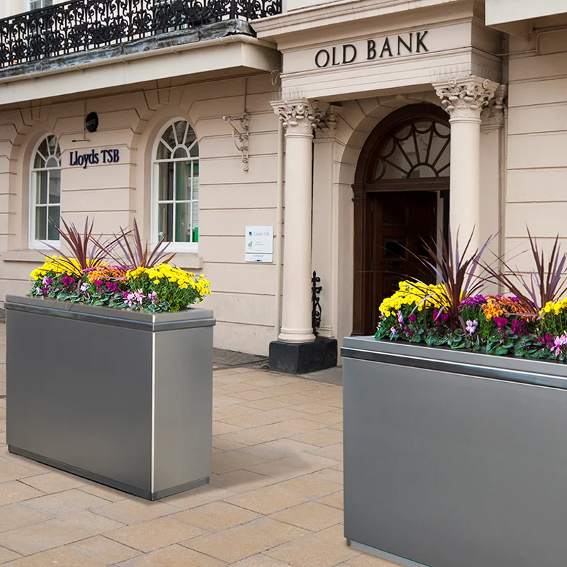 PAS 68 impact-rated stainless steel security planter shrouds installed at a historic bank entrance in the UK